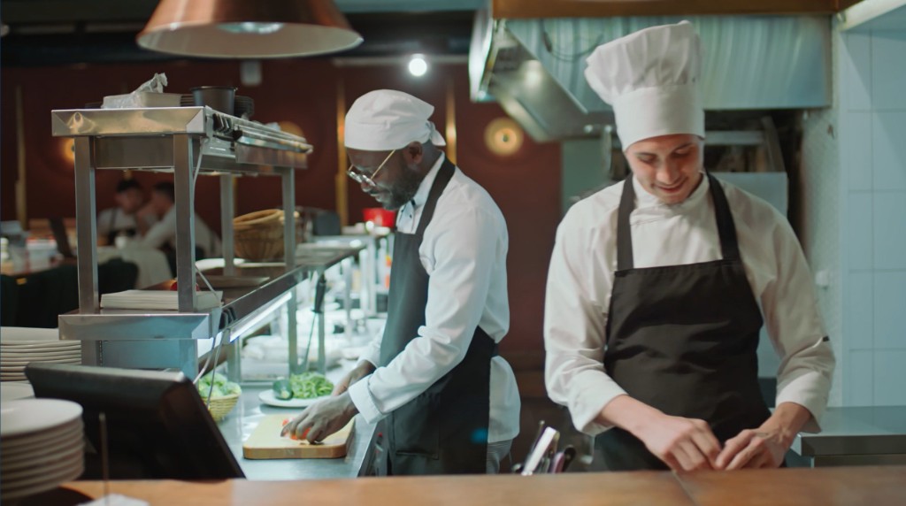 Two chefs preparing food in a commercial kitchen